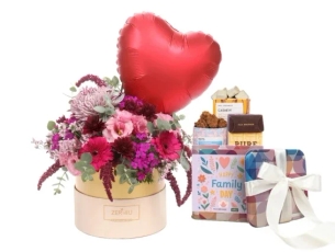 סידור פרחים בגווני ורוד וסגול, בשילוב מארז שוקולד ובלון הליום. מגיע בקופסה עגולה