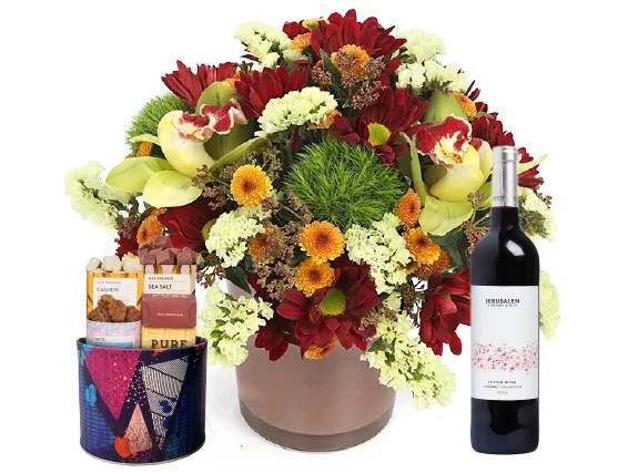 סידור פרחים 'ארגמן' בגווני אדום, כתום, חום וירוק בשילוב בקבוק יין אדום ומארז שוקולד