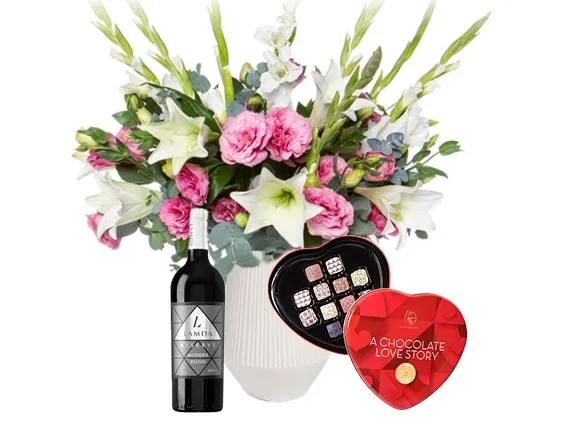 זר פרחים בגווני ורוד ולבן, בשילוב בקבוק יין אדום ופרליני אהבה