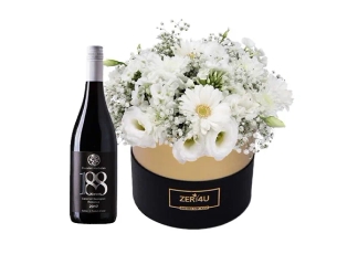 סידור פרחים בגווני לבן בקופסה שחור זהב, בשילוב בקבוק יין אדום מיקב בזלת הגולן